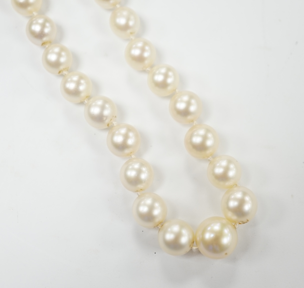 A single strand graduated cultured pearl necklace, with three stone diamond set white metal clasp, 44cm, Fair condition.